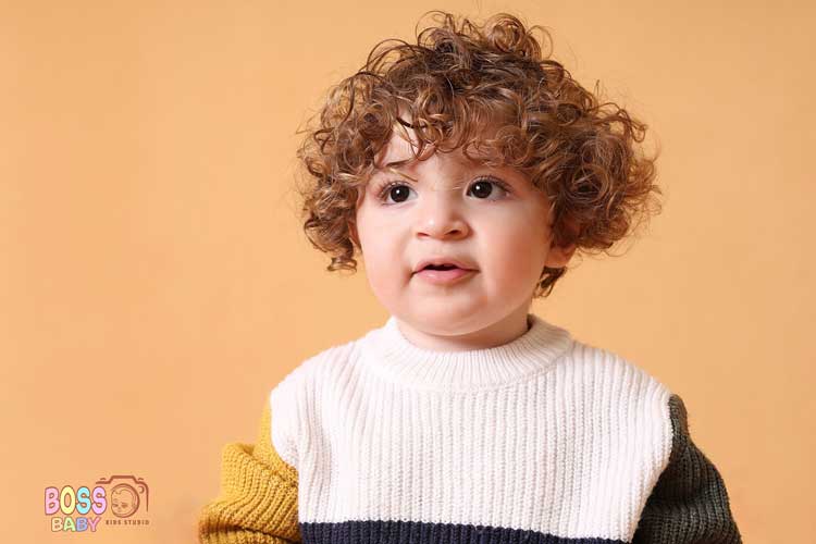 ایده عکس پاییزی کودک با کدوهای تزئینی و برگهای رنگارنگ در آتلیه